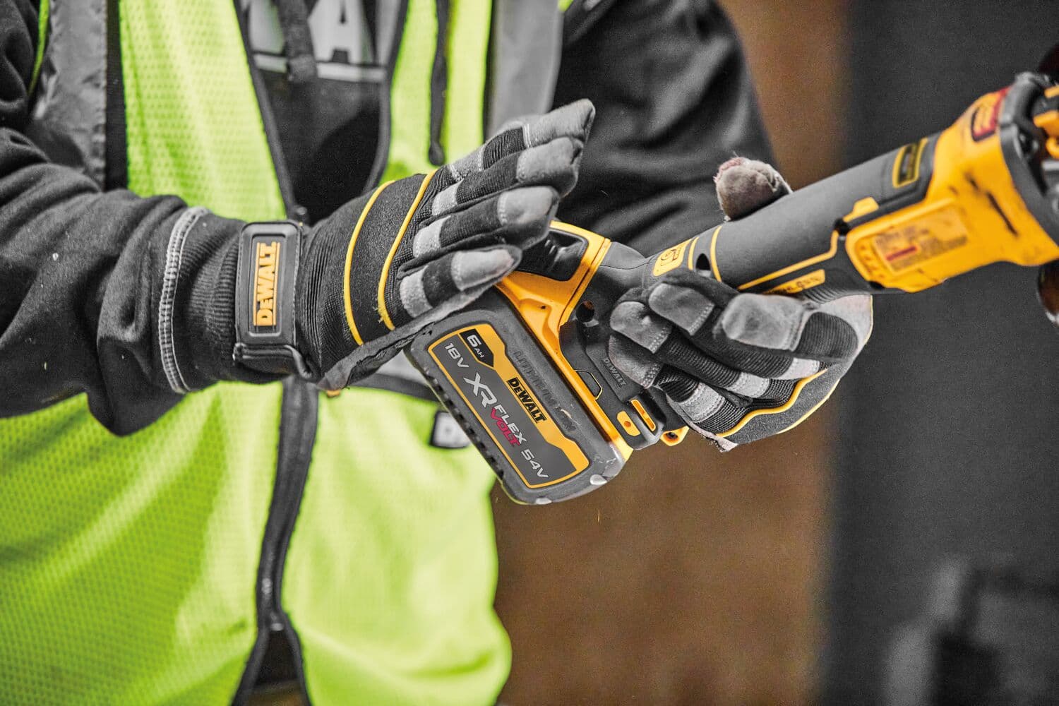 Persona con guantes sostiene herramienta DEWALT XR FLEXVOLT inalámbrica y chaleco de seguridad amarillo.