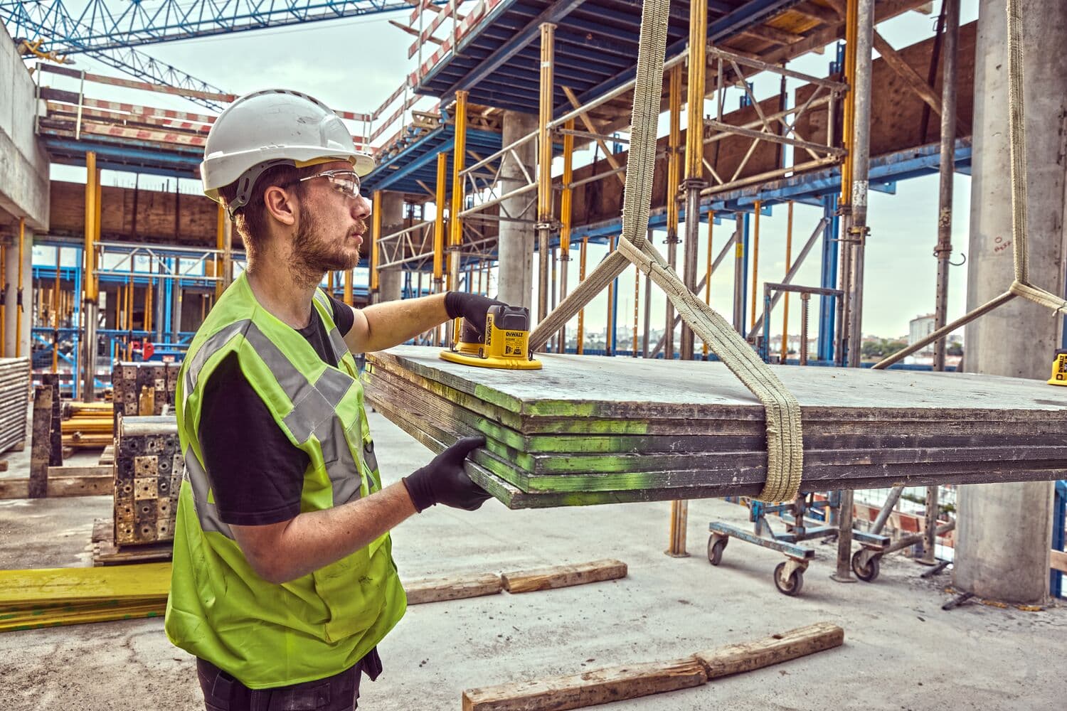 Trabajador con equipo seguro usa DEWALT DCE590 sobre placas metálicas en obra.