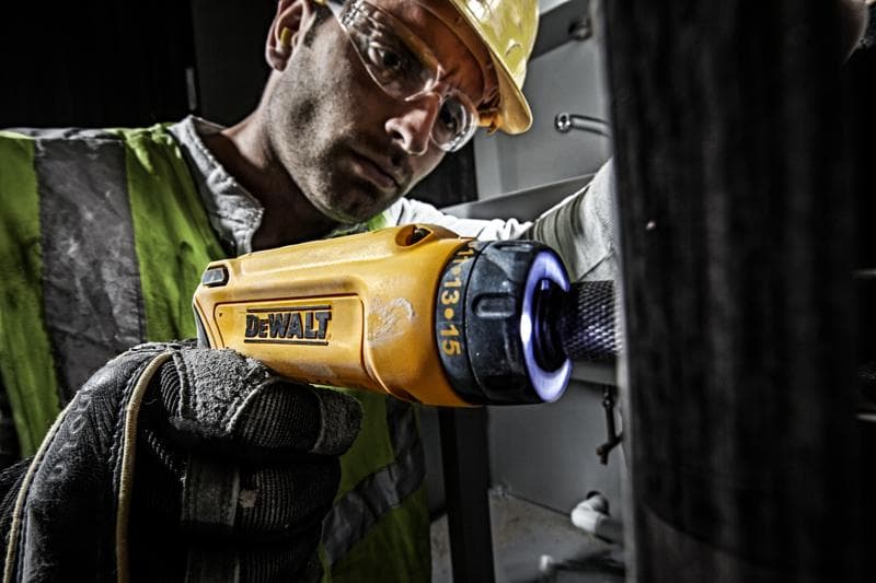 Persona utiliza destornillador DEWALT DCF680G2 amarillo con guante en entorno industrial.