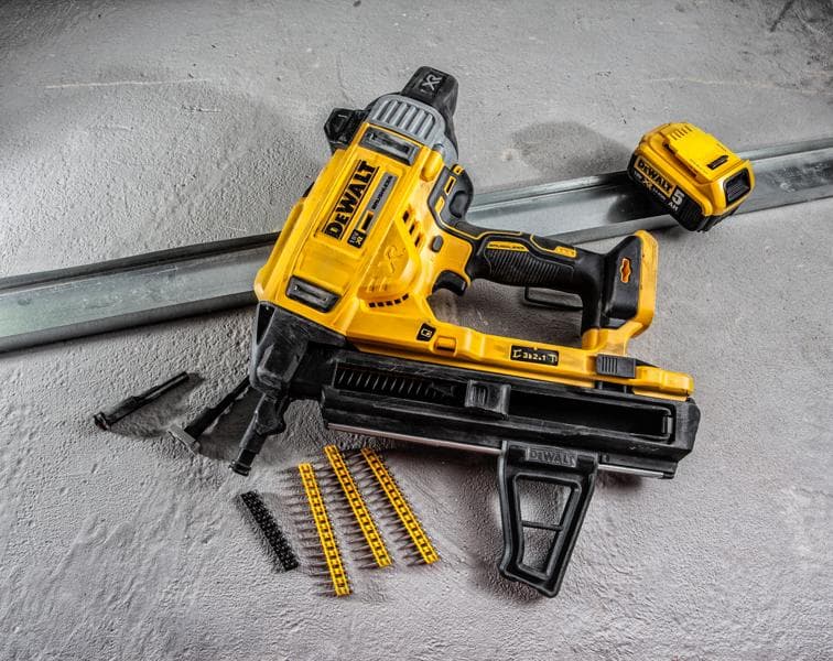Clavadora a batería DEWALT DCN890P2 con accesorios y fijaciones sobre superficie de concreto.