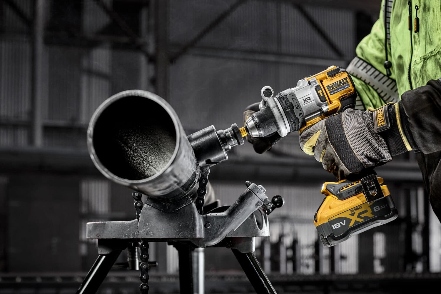 Persona usando taladro inalámbrico DEWALT para trabajar en tubo metálico en ambiente industrial.
