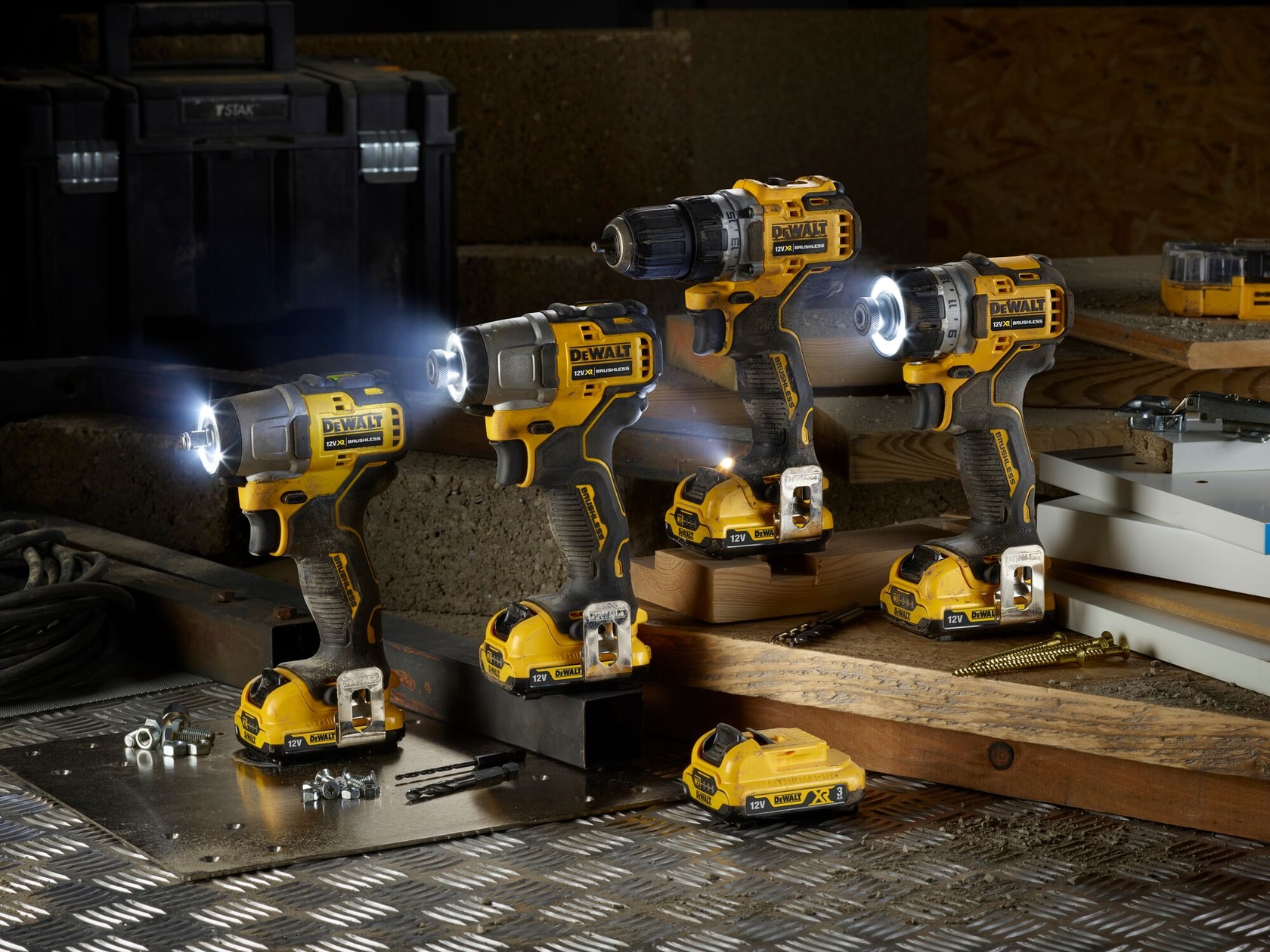 Tres herramientas eléctricas inalámbricas DEWALT con luces LED están colocadas sobre una mesa de trabajo junto a una batería