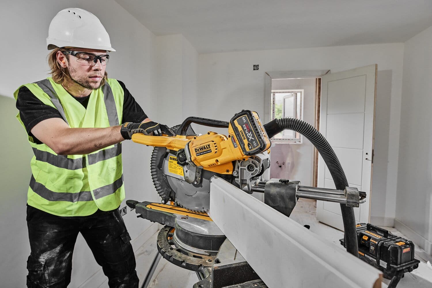 Trabajador corta madera con la sierra ingletadora DEWALT DCS781N, usando equipo de seguridad.