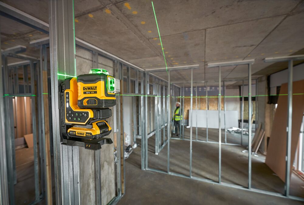 Nivel láser verde DEWALT montado en perfil metálico para alineación en edificio sin terminar.
