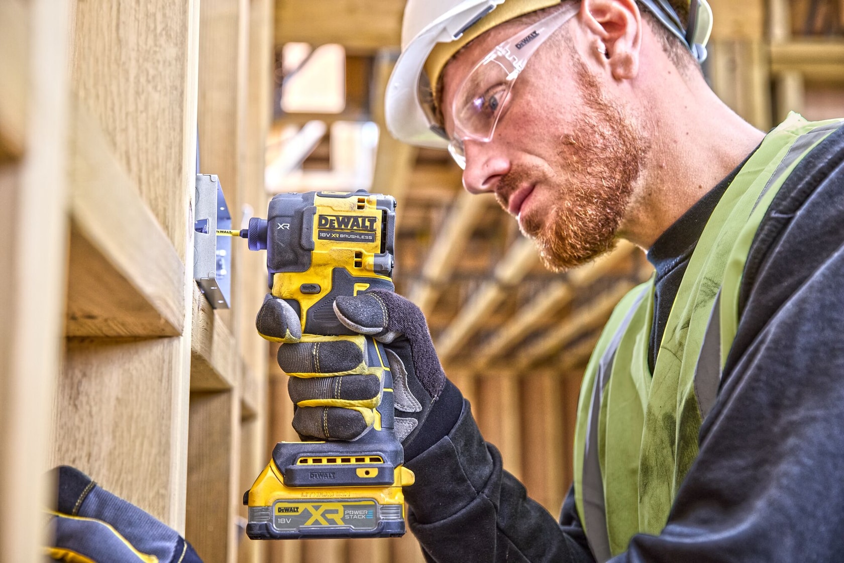 Trabajador usa atornillador de impacto inalámbrico DEWALT DCF870NT en estructura de madera.