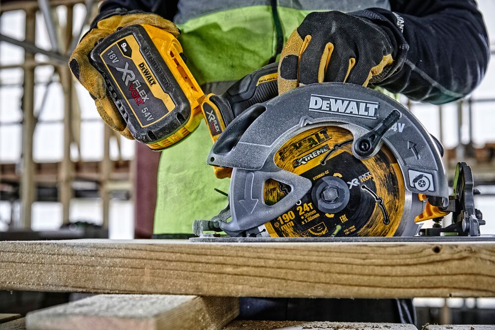 Sierra circular DEWALT inalámbrica corta madera, persona con guantes usa herramienta en obra.
