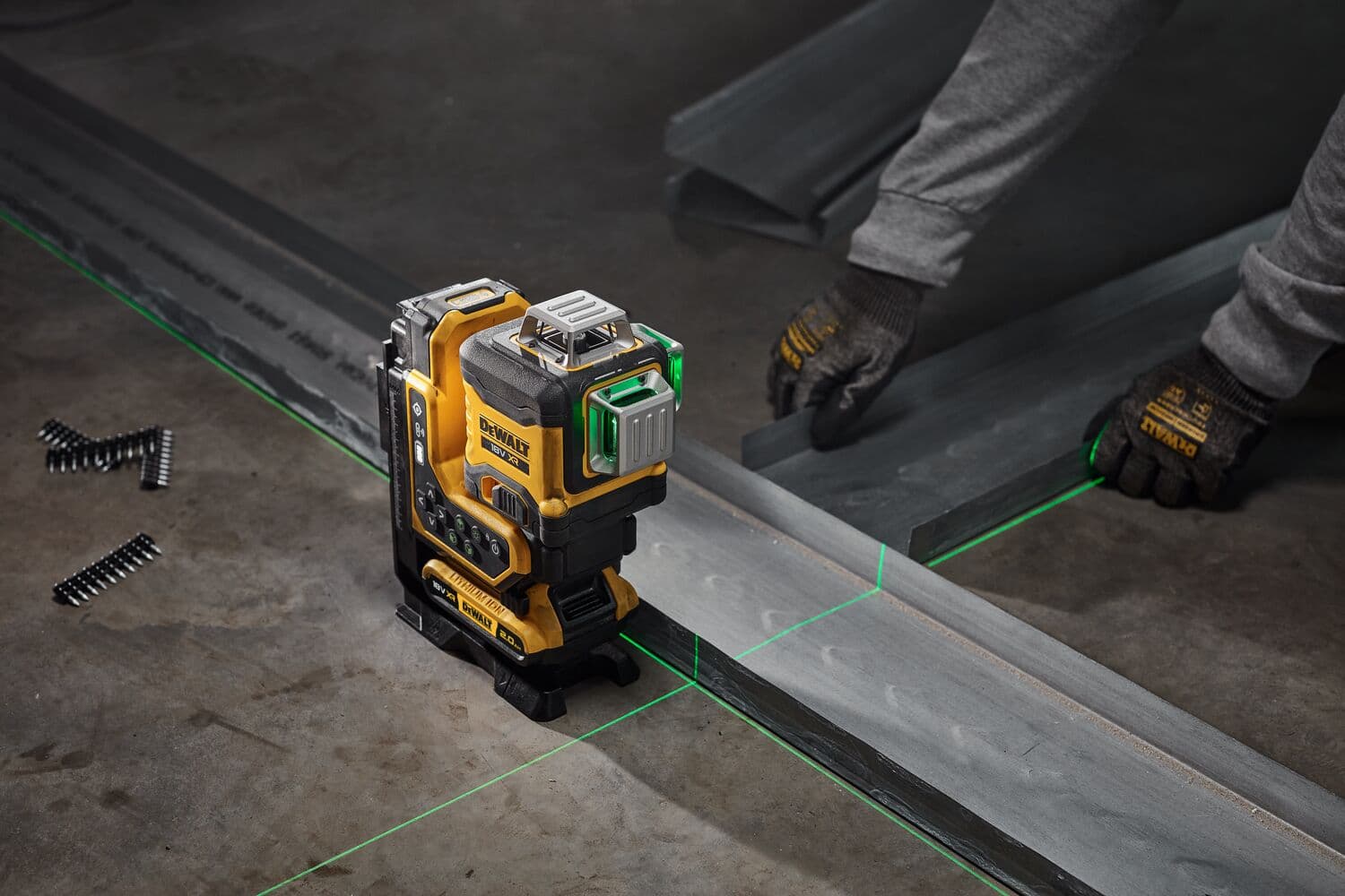 Nivel láser DEWALT proyecta líneas verdes sobre rieles metálicos para alineación en construcción.