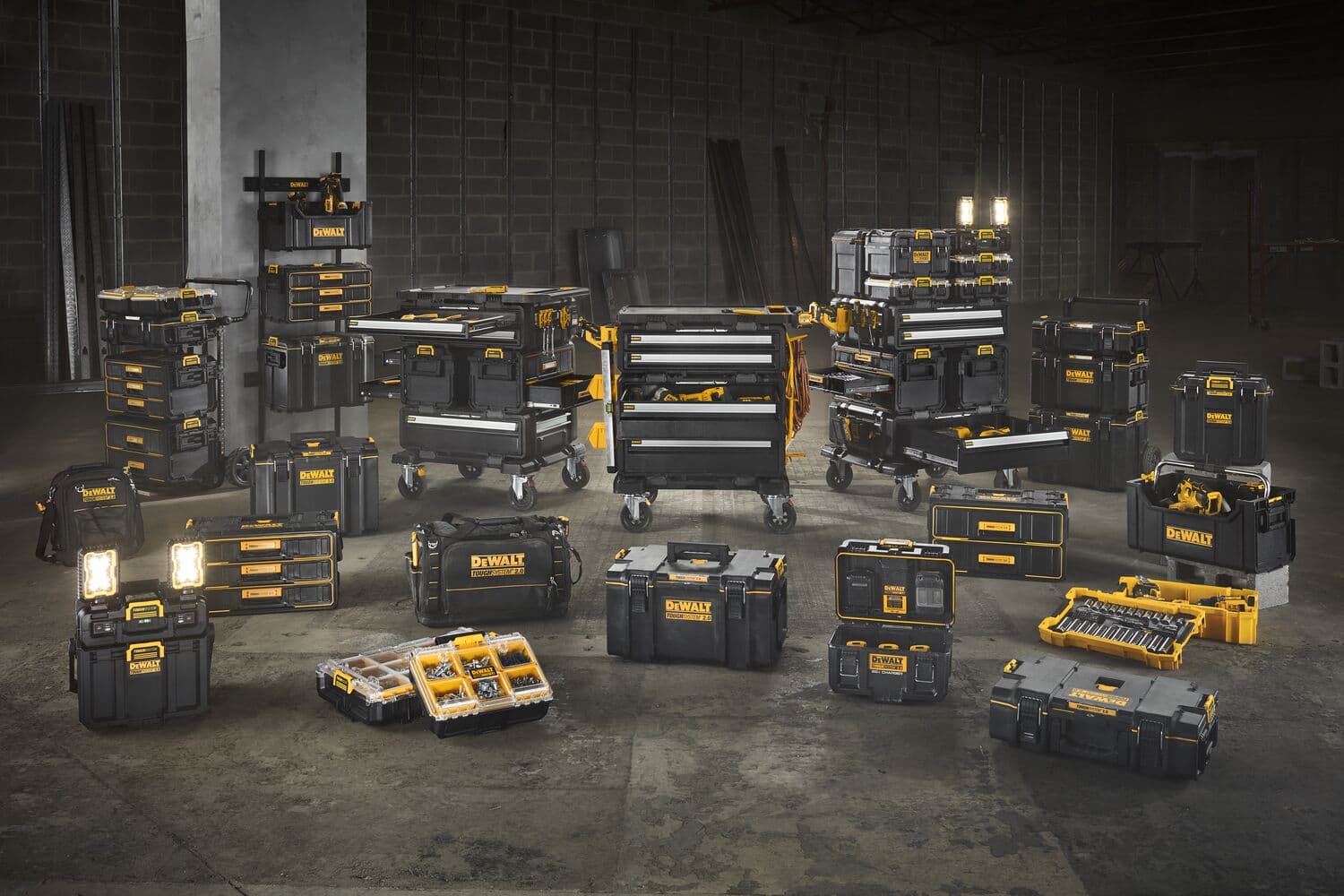 Una variedad de unidades de almacenamiento de herramientas, cajas de herramientas, organizadores y estaciones de trabajo móviles de la marca DEWALT en negro y amarillo se muestran juntos en un entorno de almacén. Los artículos están dispuestos en filas y pilas, mostrando diferentes tamaños y configuraciones para guardar y transportar herramientas.